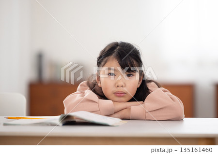 憂鬱な表情でテーブルに伏せる小学生の女の子 憂鬱な表情でテーブルに伏せる小学生の女の子 135161460