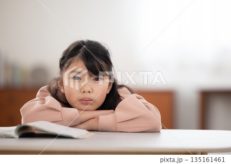 憂鬱な表情でテーブルに伏せる小学生の女の子 憂鬱な表情でテーブルに伏せる小学生の女の子 135161461