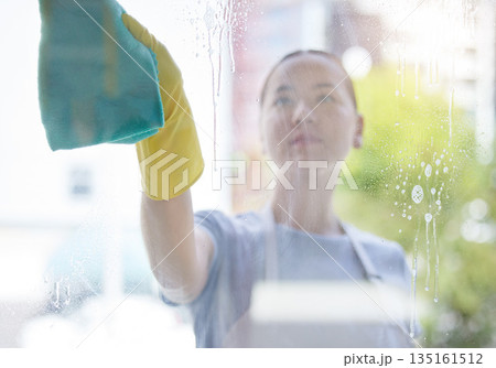 Wipe, window and cleaning with a woman housekeeper using disinfectant to remove bacteria in a home. Safety, glass and hygiene with a young female cleaner working in a domestic house for service 135161512