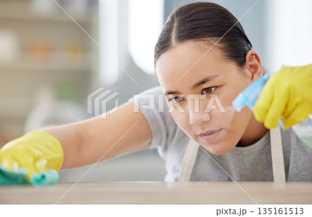Spray, table and cleaning with a woman housekeeper using disinfectant to remove bacteria in a home. Safety, surface and hygiene with a young female cleaner working in a house living room for service 135161513