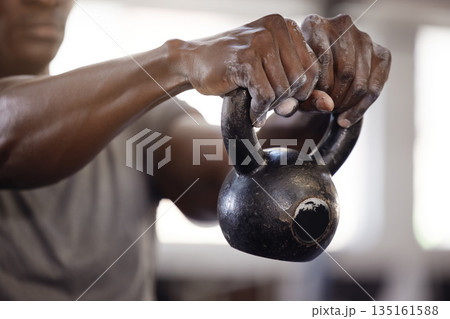 Kettlebell, hands and exercise with a man at gym for fitness, training and strong muscle growth. Athlete or bodybuilder person at club for iron weights workout for power and performance with powder 135161588