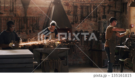 Hammer, anvil and sparks with a men working in a foundry for metal work manufacturing or production. Industry, welding and trade with a blacksmith people in a workshop, plant or industrial forge Hammer, anvil and sparks with a men working in a foundry for metal work manufacturing or production. Industry, welding and trade with a blacksmith people in a workshop, plant or industrial forge 135161815