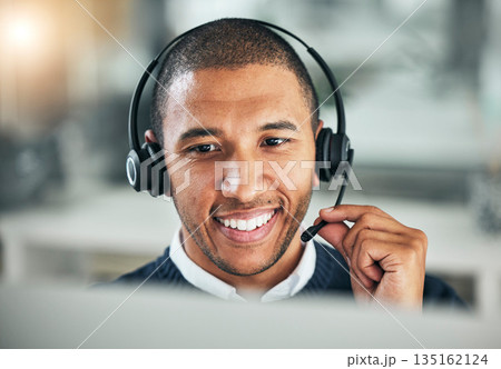 Face, call center and a man with a headset at computer for customer service or sales. Smile of african person at a pc and talking on microphone as telemarketing, crm support or help desk consultant 135162124