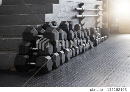 Equipment, gym weights and floor of room or empty facility for fitness, sports and exercise club mockup. Dumbbells, barbell stack and weight rack in a dark training gymnasium for workout class 135162168