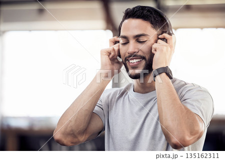 Headphones, listening to music and a man at gym for exercise, fitness or training workout. Face of happy male athlete listen to audio, sound or radio with tech for motivation, mindset and to relax 135162311