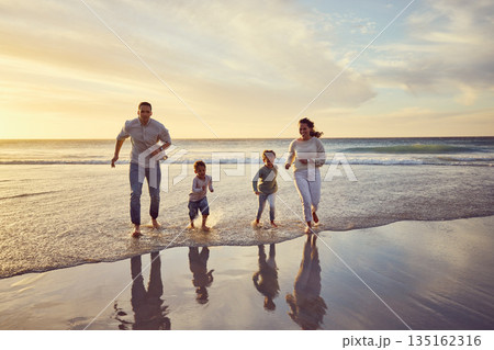 Beach, sunset and parents play with kids on holiday, summer vacation and weekend together. Nature, family and happy mother, father and children run in ocean for bonding, adventure and quality time 135162316