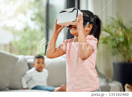 Young girl with VR goggles, gaming and metaverse with futuristic tech, child experience simulation at family home. Female kid in living room with video games, virtual reality and future technology Young girl with VR goggles, gaming and metaverse with futuristic tech, child experience simulation at family home. Female kid in living room with video games, virtual reality and future technology 135162460