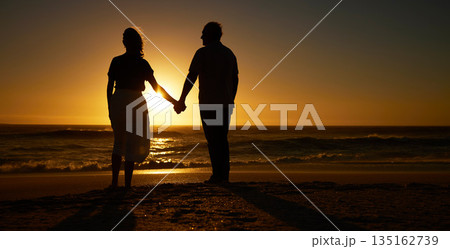 Beach, sunset and a silhouette couple holding hands on vacation or holiday outdoor. Behind man and woman in nature with creative art, mockup space and ocean for love, care and travel or freedom 135162739