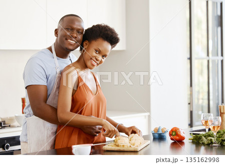 Portrait, hug and black couple in a kitchen for cooking, meal and bonding in their home together. Food, face and happy woman and man with love preparing dinner with bread, nutrition and vegetable 135162998