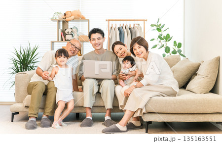 リビングルームでパソコンを見ながらくつろぐ三世代家族,ファミリー（団らん） 135163551