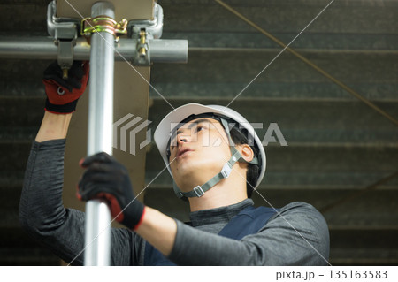工場現場で単管パイプを組む作業員 工場現場で単管パイプを組む作業員 135163583