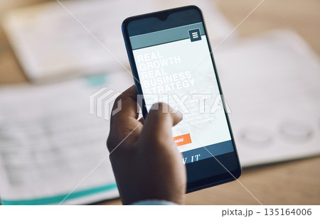 Phone, research and strategy with a business man at a desk in his office for work while planning growth. Hand, mobile and internet with a male employee reading information or data online closeup 135164006