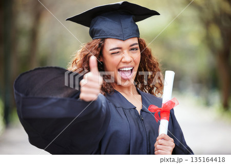 Thank you, portrait of college student with thumbs up and winking for success at her campus outdoors. Achievement, graduate and female person with her certificate or diploma at university outside Thank you, portrait of college student with thumbs up and winking for success at her campus outdoors. Achievement, graduate and female person with her certificate or diploma at university outside 135164418