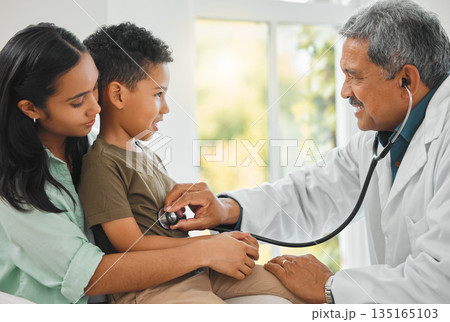 Doctor checking a kid patient with stethoscope on a sofa for home medicare consultation. Healthcare, pediatrician and mother sitting with her boy child for male medical worker to listen to breathing. Doctor checking a kid patient with stethoscope on a sofa for home medicare consultation. Healthcare, pediatrician and mother sitting with her boy child for male medical worker to listen to breathing. 135165103