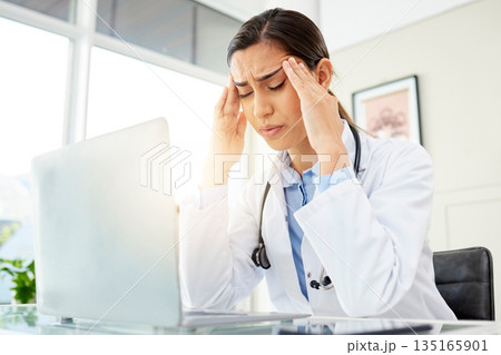 Mental health, woman doctor with a headache and with laptop at her desk in a workplace office with a lens flare. Stress or depression, problem or mistake and female surgeon sad at her workstation Mental health, woman doctor with a headache and with laptop at her desk in a workplace office with a lens flare. Stress or depression, problem or mistake and female surgeon sad at her workstation 135165901