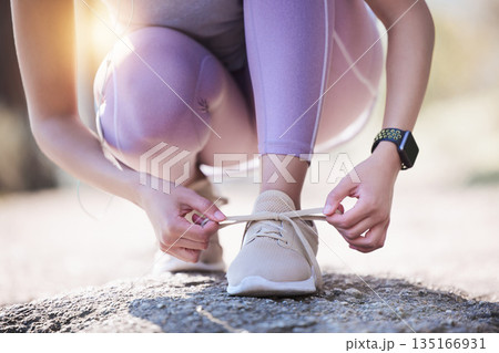 Woman, hands and tie shoes for running, exercise or workout on asphalt road or street outdoors. Hand of female person or runner tying shoe getting ready for walk, run or fitness exercising in nature 135166931