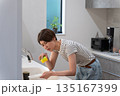 キッチンで皿洗いをする体調不良の女性 135167399