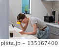 キッチンで皿洗いをする体調不良の女性 135167400