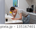 キッチンで皿洗いをする体調不良の女性 135167401
