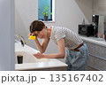 キッチンで皿洗いをする体調不良の女性 135167402