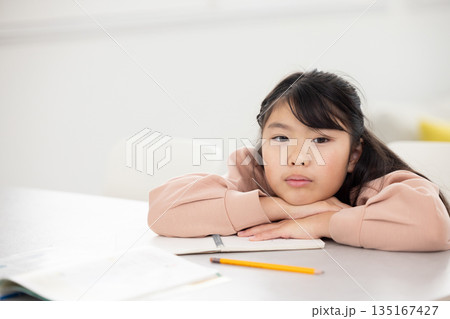 憂鬱な表情でテーブルに伏せる小学生の女の子 憂鬱な表情でテーブルに伏せる小学生の女の子 135167427