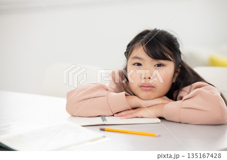 憂鬱な表情でテーブルに伏せる小学生の女の子 憂鬱な表情でテーブルに伏せる小学生の女の子 135167428