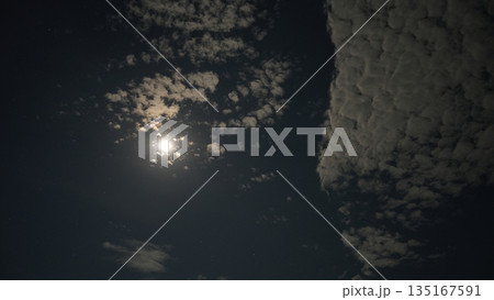 Bright moon shining through scattered clouds at night Bright moon shining through scattered clouds at night 135167591