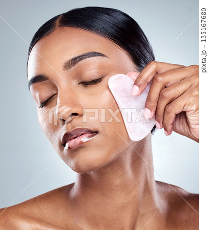 Beauty, facial and gua sha with face of woman in studio for massage, wellness and cosmetics. Spa, self care and glow with model on grey background for skincare, cosmetology and rose quartz crystal 135167680
