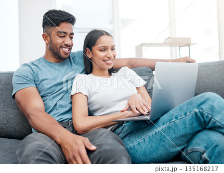 Couple, laptop and watching a video on a lounge sofa with happiness and love at home. Computer, streaming series and young people together on a living room couch in a house with tech and a smile 135168217