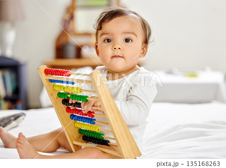 Abacus, bed and portrait of baby with toy for learning, child development and motor skills. Family home, newborn and face of adorable child with educational toys, counting beads and fun in bedroom Abacus, bed and portrait of baby with toy for learning, child development and motor skills. Family home, newborn and face of adorable child with educational toys, counting beads and fun in bedroom 135168263