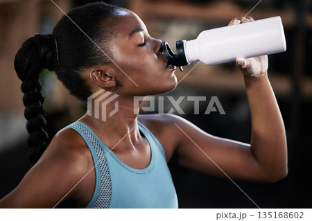 Tired, fitness or black woman drinking water in gym after training, workout or exercise to relax or hydrate body. Fatigue, fitness or girl with bottle for healthy liquid hydration on resting break Tired, fitness or black woman drinking water in gym after training, workout or exercise to relax or hydrate body. Fatigue, fitness or girl with bottle for healthy liquid hydration on resting break 135168602