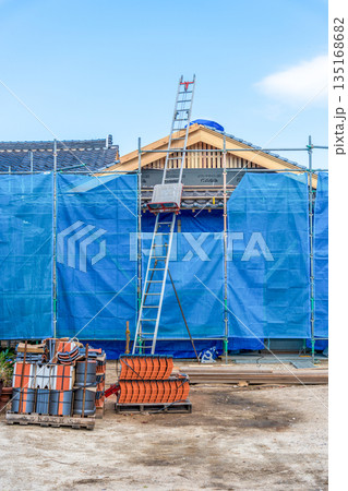 住宅イメージ　新築中の木造住宅に屋根瓦を上げる瓦上げ機 135168682