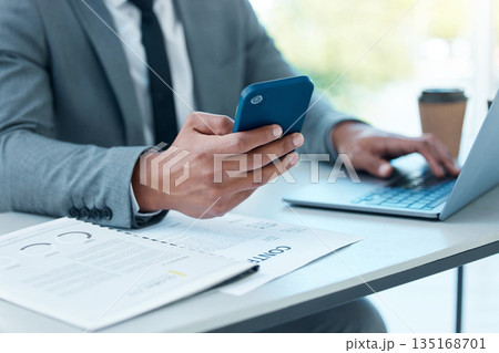 Hands of man with laptop, phone and desk at startup checking email, social media and search on internet at business. Online report, networking and businessman in office typing or reading on cellphone 135168701