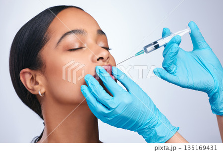 Woman, studio and needle for lips, surgery and cosmetics for skin, facial or collagen by white background. Girl cosmetic surgeon and filler on face, syringe and hands for beauty, skincare and mouth Woman, studio and needle for lips, surgery and cosmetics for skin, facial or collagen by white background. Girl cosmetic surgeon and filler on face, syringe and hands for beauty, skincare and mouth 135169431