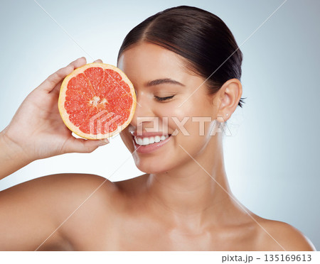Face smile, skincare and woman with grapefruit in studio isolated on a white background. Vegan, natural and female model with fruit for vitamin c, nutrition or healthy diet, wellness or cosmetics. Face smile, skincare and woman with grapefruit in studio isolated on a white background. Vegan, natural and female model with fruit for vitamin c, nutrition or healthy diet, wellness or cosmetics. 135169613