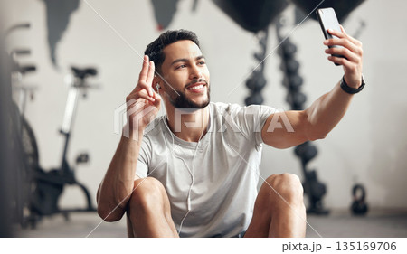 Man, gym and selfie with happiness for exercise with motivation and wellness with peace sign. Male person, training and video call for a workout for sports and conversation with smile at a club. Man, gym and selfie with happiness for exercise with motivation and wellness with peace sign. Male person, training and video call for a workout for sports and conversation with smile at a club. 135169706