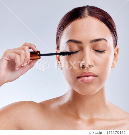 Beauty, face and woman with mascara makeup, cosmetics and product brush on eye, lashes and studio background. Cosmetic, closed eyes and model with eyelashes tool for make up, skincare and self care 135170132