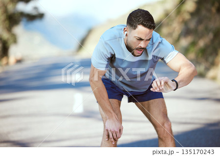 Man, fitness and outdoor with a watch for a run or exercise with performance progress. Tired athlete person or runner on a road with time and music for training, running or health and wellness goals 135170243