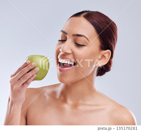 Apple, happy or woman in studio eating on white background for healthy nutrition or clean diet. Bite, smile or hungry beautiful girl advertising or marketing natural organic green fruits for wellness 135170281