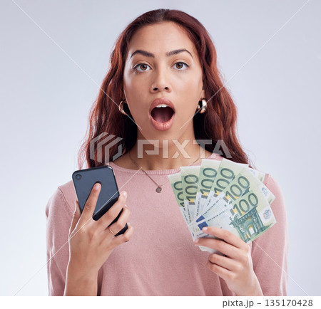 Investment, money or shocked woman with phone for online investment on digital fintech in studio. Financial mobile app, ecommerce payment or surprised girl typing banking data on internet with Euros Investment, money or shocked woman with phone for online investment on digital fintech in studio. Financial mobile app, ecommerce payment or surprised girl typing banking data on internet with Euros 135170428
