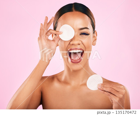 Happy woman, face and cotton pad in skincare, makeup removal or cosmetics against a pink studio background. Portrait of excited female person with cosmetic swab in beauty cleaning or facial treatment 135170472