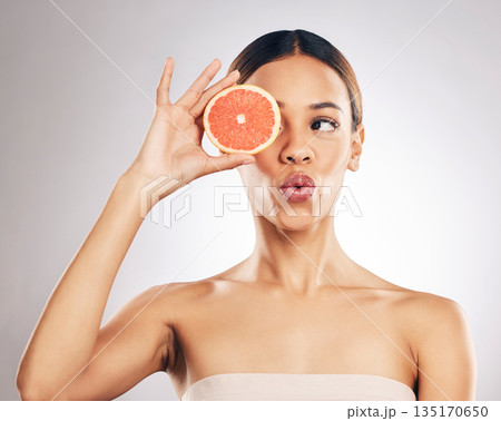 Grapefruit, skincare and woman in studio for natural cosmetic, treatment and beauty on grey background. Citrus, facial and female model relax with fruit for vegan, detox and vitamin c or glowing skin 135170650