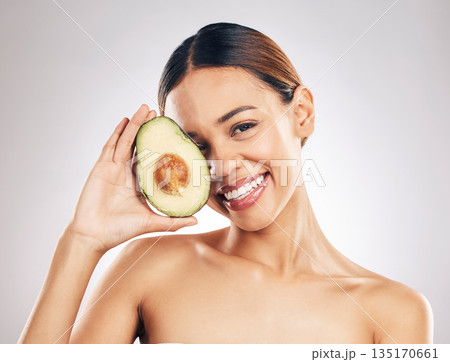 Woman, skincare and avocado in studio portrait for health, wellness or facial glow by white background. Girl, model and healthy skin with fruit, makeup or cosmetics for self care, aesthetic and smile 135170661