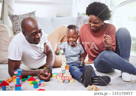 Building blocks, games and black family playing on a living room floor happy, love and bonding in their home. Child development, learning and kid with parents in lounge with alphabet, shape and toys 135170957