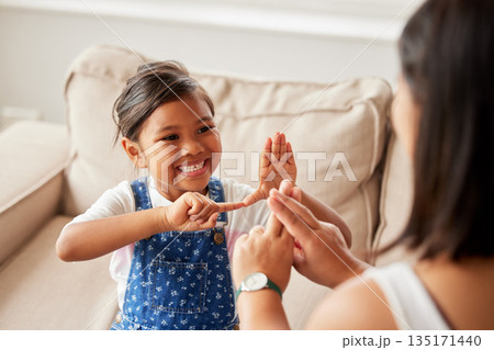 Sign language, learning and girl kid with her mother in the living room of their family home. Happy, smile and child speaking with her hands to her deaf mom to communicate in their modern house. Sign language, learning and girl kid with her mother in the living room of their family home. Happy, smile and child speaking with her hands to her deaf mom to communicate in their modern house. 135171440