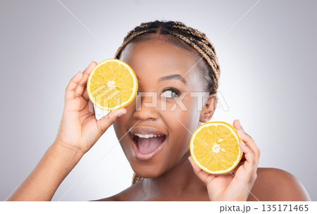 Glow, orange and skincare with black woman in studio for natural, cosmetics and vitamin c. Nutrition, diet and detox with face of female model on grey background for citrus fruit and health product Glow, orange and skincare with black woman in studio for natural, cosmetics and vitamin c. Nutrition, diet and detox with face of female model on grey background for citrus fruit and health product 135171465
