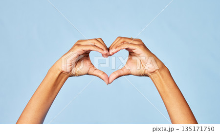 Hands, heart and emoji with a person in studio on a blue background for love, health or social media. Affection, romantic and hand gesture with an adult indoor to show a sign or icon of romance Hands, heart and emoji with a person in studio on a blue background for love, health or social media. Affection, romantic and hand gesture with an adult indoor to show a sign or icon of romance 135171750