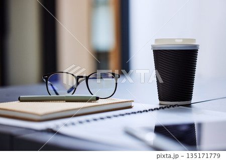 Coffee, notebook and glasses on desk in office for planning, schedule and agenda. Administration, lunch break and creative with stationary and cup on table for business, corporate and journal Coffee, notebook and glasses on desk in office for planning, schedule and agenda. Administration, lunch break and creative with stationary and cup on table for business, corporate and journal 135171779
