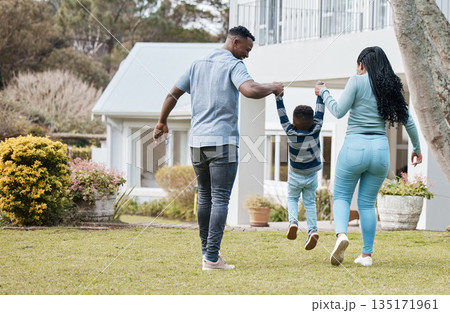 Mother and father lifting child by their new home in the outdoor garden while playing together. Backyard, bonding and back of African parents holding their boy kid in the backyard of their house. Mother and father lifting child by their new home in the outdoor garden while playing together. Backyard, bonding and back of African parents holding their boy kid in the backyard of their house. 135171961