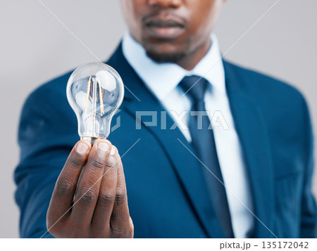 Energy, hand and businessman with light bulb for idea, knowledge or inspiration for corporate business strategy. Electricity, lightbulb and black man with creative solution, innovation or closeup 135172042